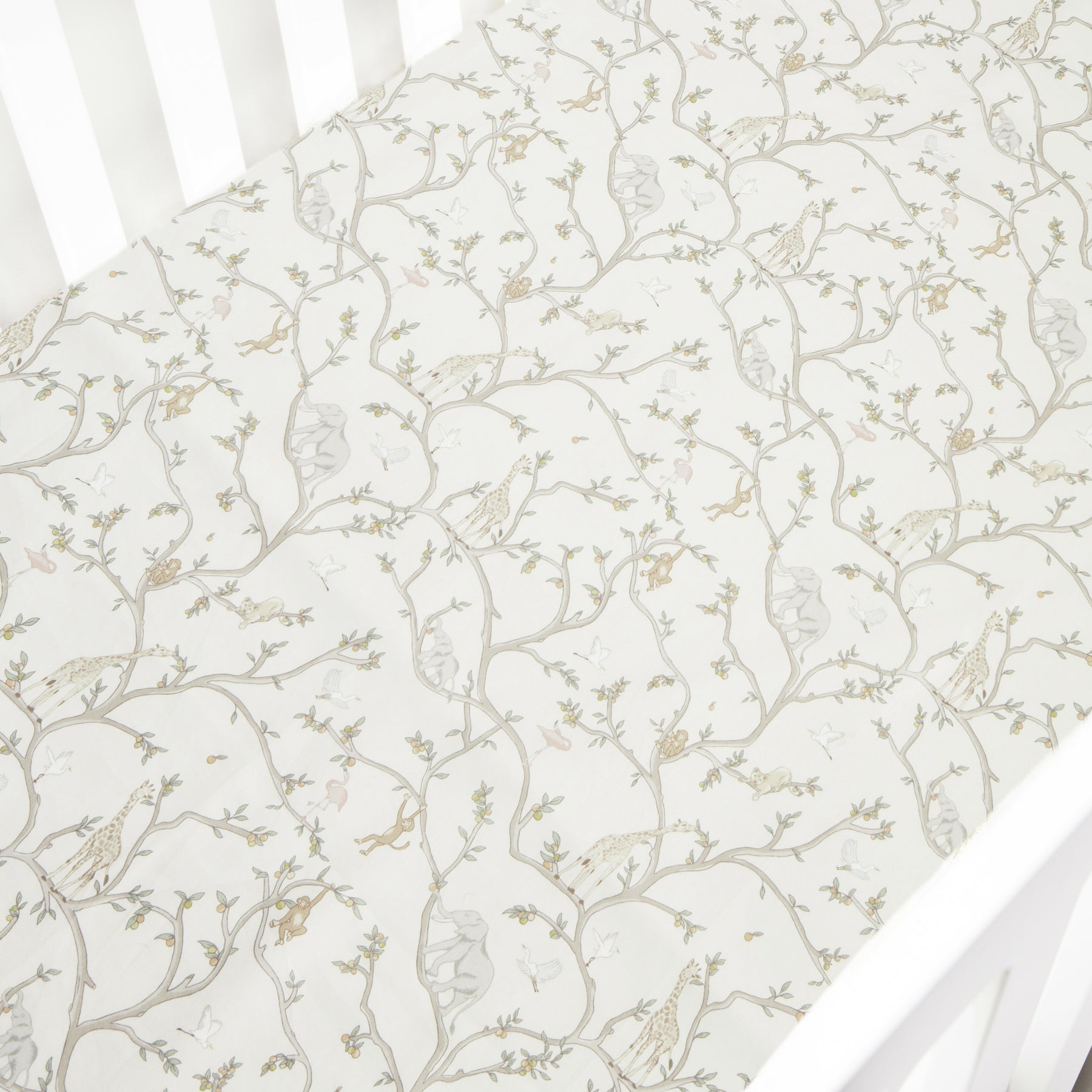 The Gooselings Animal Parade Ivory Crib Sheet is an extra soft cotton sateen sheet for crib mattresses, featuring a delicate pattern of neutral-tone animal designs.