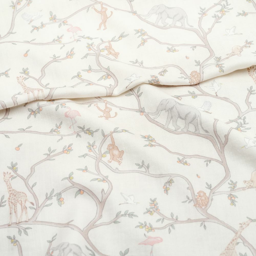 The Gooselings Animal Parade Ivory Swaddle is a 100% cotton blanket featuring whimsical trees, elephants, giraffes, monkeys, birds, and fruits in soft muted tones—ideal for cozy swaddling.