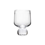 The Simon Pearce Benson Drinkware Collection features a clear glass cup with a wide bowl and rounded base, photographed on white, highlighting its clean lines inspired by Bauhaus simplicity.