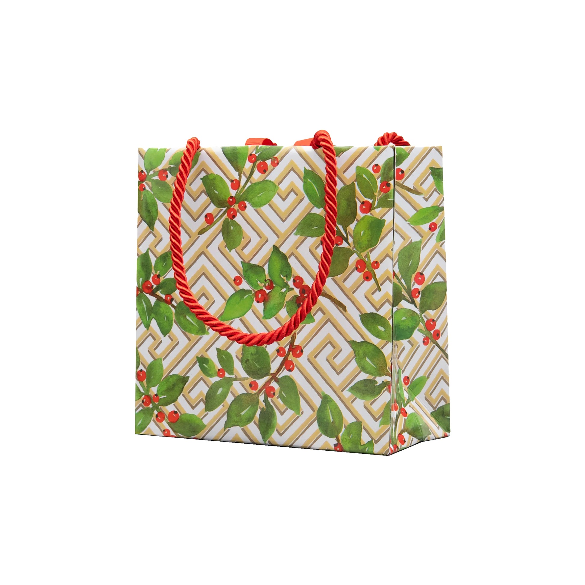 The Caspari Holly and Fretwork White Collection gift bag features a geometric gold-and-white background with green leaves, red berries, and red twisted rope handles—ideal for pairing with festive paper plates or dinnerware.