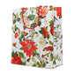 The Caspari Christmas Chinoiserie White Collection gift bag features red braided handles and colorful floral designs on white—perfect for pairing with party plates or disposable tableware at your next celebration.