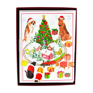 Caspari’s Pets With Model Train Christmas Card Set features two dogs and a cat in Santa hats by a decorated tree, presents, and a toy train—perfect for holiday greetings, printed on quality cardstock by an FSC-certified printer.