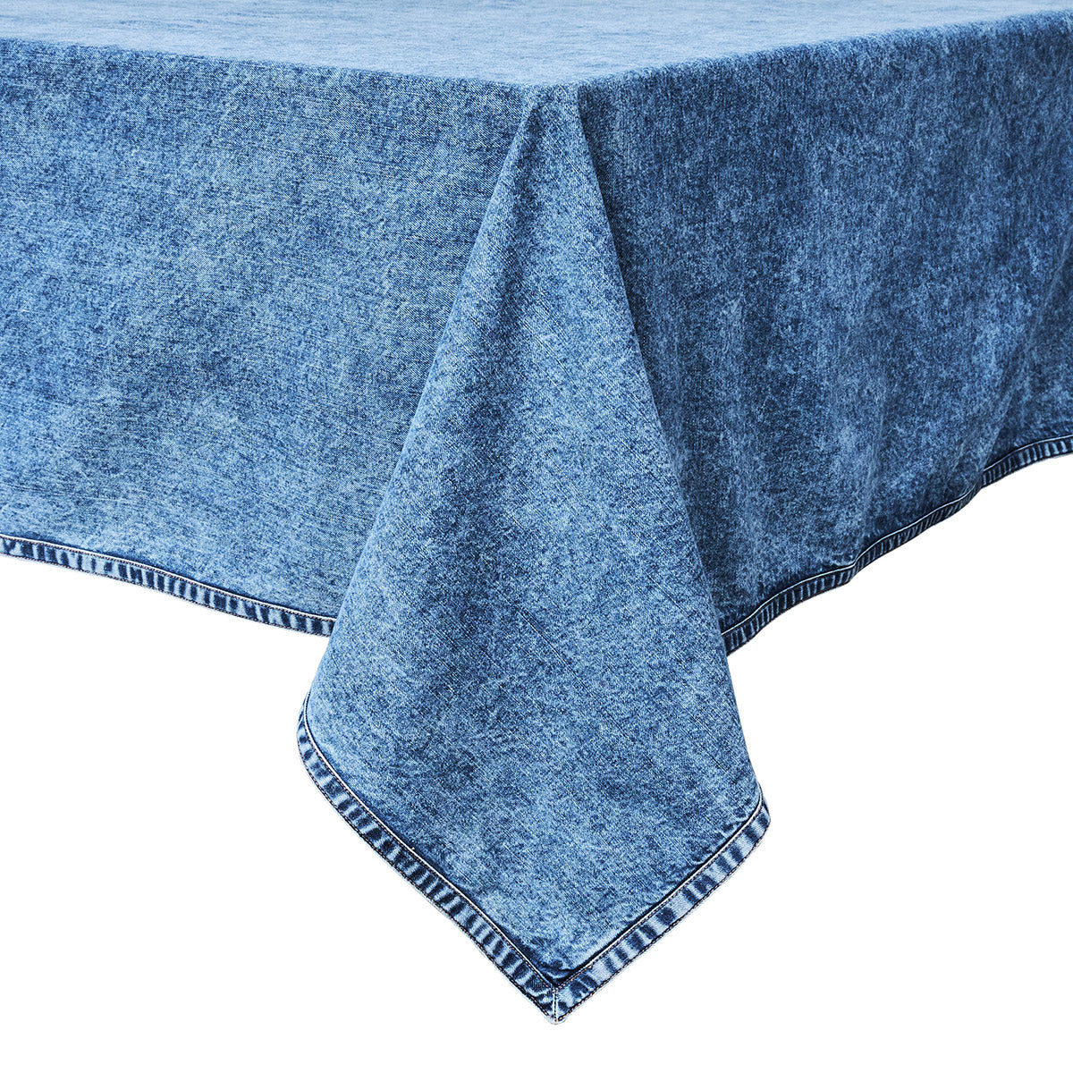 The Juliska Blue Denim Tablecloth, featuring a denim-like texture and striped edging, is draped over a rectangular table against a white background.