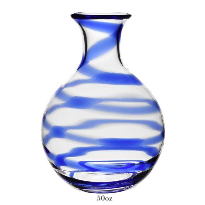 The Bella Blue Carafe Collection by William Yeoward Crystal features clear glass vases with a round base, narrow neck, and blue swirl pattern. Each carafe holds 50 oz, is ideal for serving wine or decor, and includes a Proposition 65 warning.