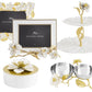 The Michael Aram Gardenia Collection features hand-enameled flowers and gold-forged leaves, with items like picture frames, a tiered tray, lidded box, and double bowl set for elegant home decor.