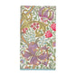 The Caspari Golden Lily Collection features a folded triple-ply napkin with an intricate floral pattern in purple, red, green, and gold on a light background.