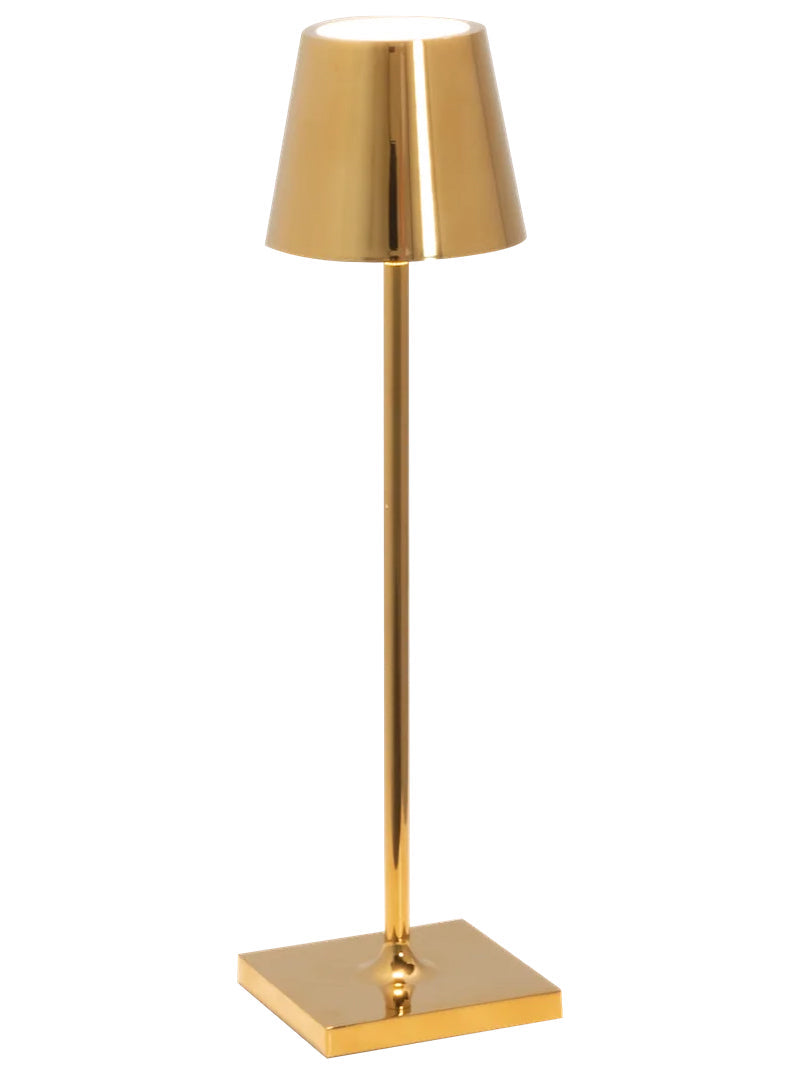 The Zafferano America Poldina Pro Micro Lamp Collection features a modern gold lamp with a conical shade and square base, adding elegance to any space. This portable, rechargeable lamp stands out beautifully against a crisp white background.