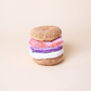 The Foggy Dog Bagel and Lox Interactive Dog Toy features pink, purple, and white layers with hidden treat pockets, crinkle, and squeak elements for added fun, shown on a plain beige background.