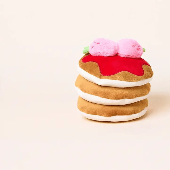The Foggy Dog’s Strawberry Pancake Interactive Dog Toy features a plush stack of pancakes topped with red syrup and two pink berries, set against a plain background.