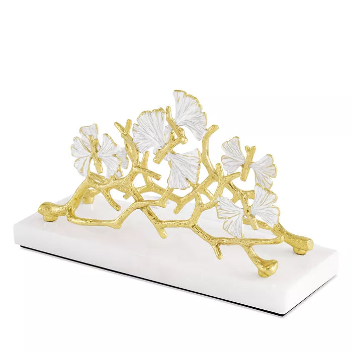 The Michael Aram Butterfly Gingko Gold Vertical Napkin Holder is a handcrafted piece featuring gold and white gingko leaves on a white base, adding elegance to any collection of decorative objects.
