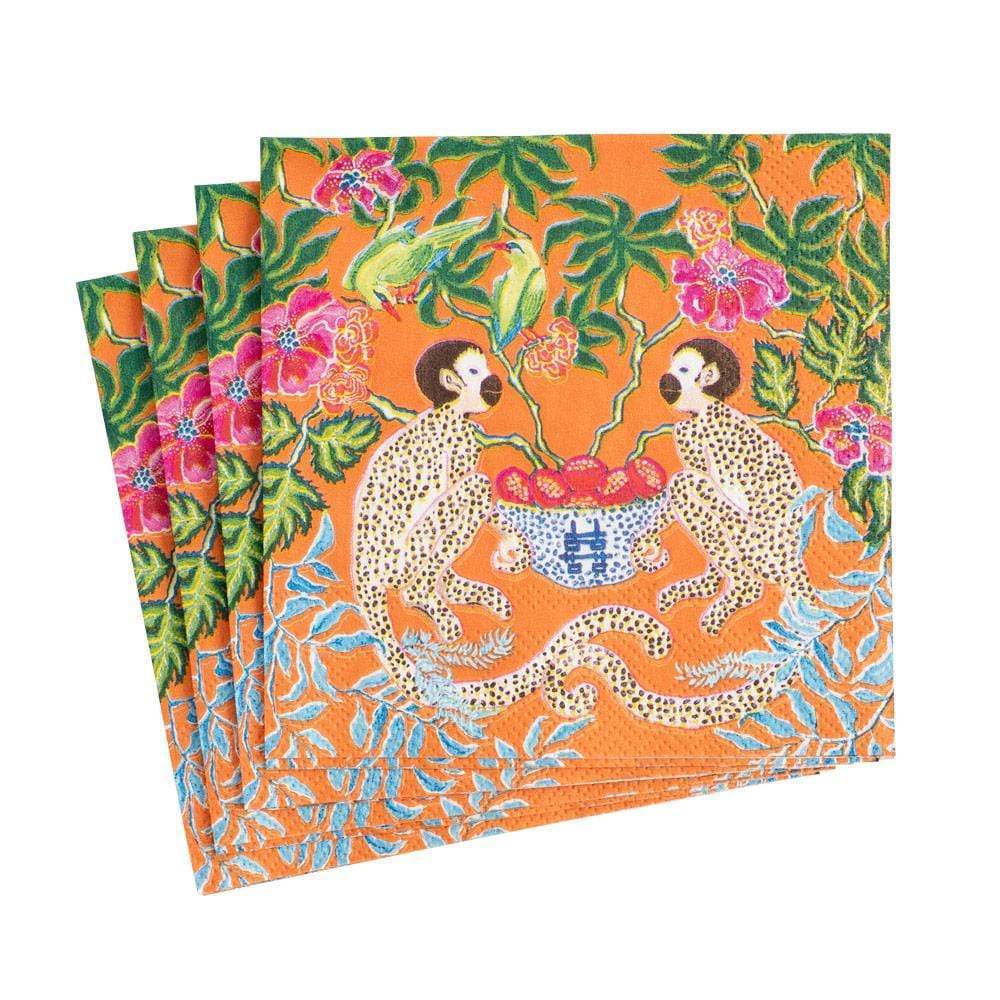 The Caspari Monkeys Orange napkins feature two monkeys by a bowl of fruit, surrounded by flowers and green foliage. Set includes four triple-ply orange napkins.