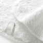 Close-up of a folded white towel from the Graccioza Egoist Bath Collection, made of Egyptian cotton terry cloth, featuring a small fabric hanging loop.