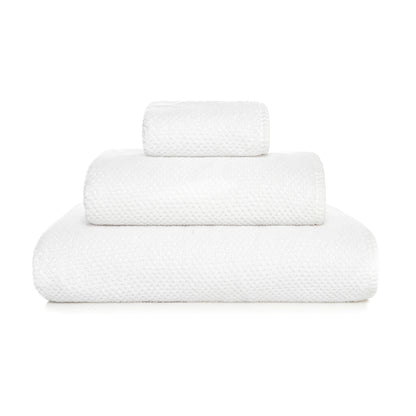 Three neatly folded white towels from the GRACCIOZA Bee Waffle Bath Collection, crafted from soft combed cotton in different sizes, are stacked atop one another against a plain white background.