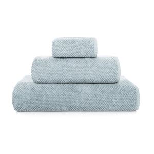 Three neatly folded blue towels from the GRACCIOZA Bee Waffle Bath Collection are stacked atop each other against a white background.