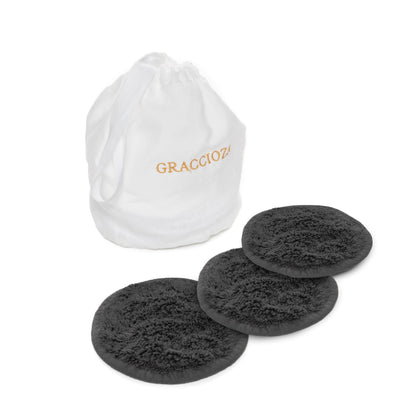 Three round black Egoist Spa Accessories makeup remover pads by Graccioza, crafted from luxurious Egyptian Cotton Giza, are displayed before a white "GRACCIOZA" drawstring bag. Ideal for gentle cleansing and pairing with your favorite hair towel.