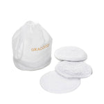 A white drawstring bag labeled "Graciozza" sits beside four textured, round white Egoist Spa Accessories reusable pads, all crafted from luxurious Egyptian Cotton Giza and displayed on a white background.