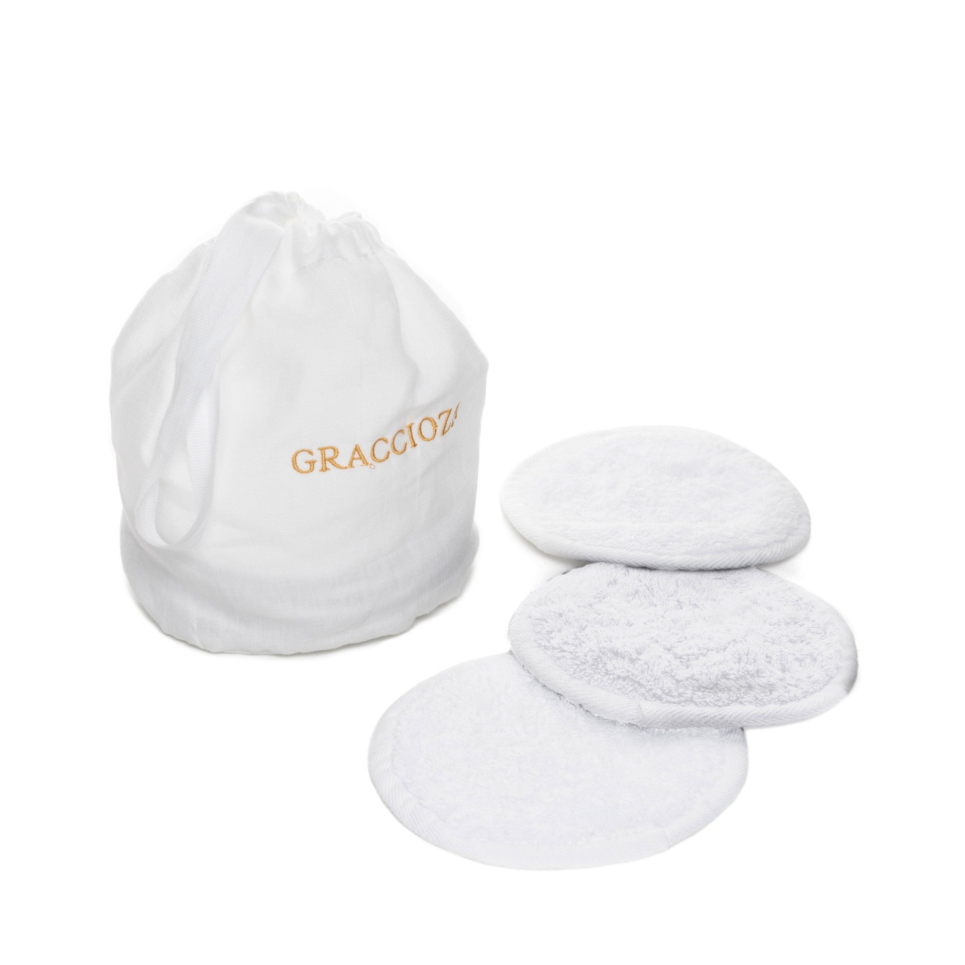 A white drawstring bag labeled "Graciozza" sits beside four textured, round white Egoist Spa Accessories reusable pads, all crafted from luxurious Egyptian Cotton Giza and displayed on a white background.
