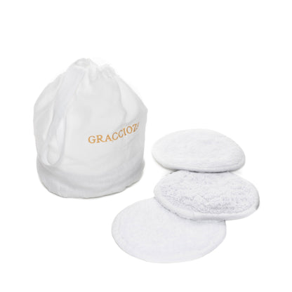 A white drawstring bag labeled "Graciozza" sits beside four textured, round white Egoist Spa Accessories reusable pads, all crafted from luxurious Egyptian Cotton Giza and displayed on a white background.