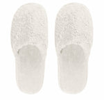 The Egoist Bath Slippers by Graccioza are white, fuzzy, closed-toe slippers crafted from high-density Egyptian cotton and viewed from above on a plain background.