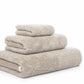 Three beige towels from the Graciozza Bicolore Bath Collection, each a different size, are neatly stacked against a white background.