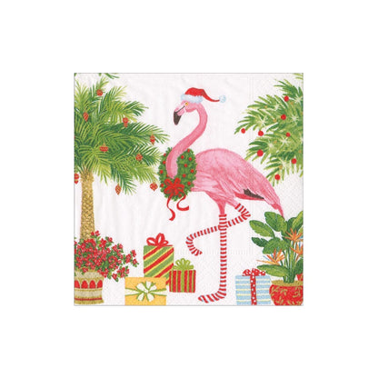 The Christmas Flamingos Napkin Collection by Caspari features a pink flamingo in a Santa hat and wreath, standing among palm trees and gifts—ideal as triple-ply guest towel or cocktail napkins for festive occasions.