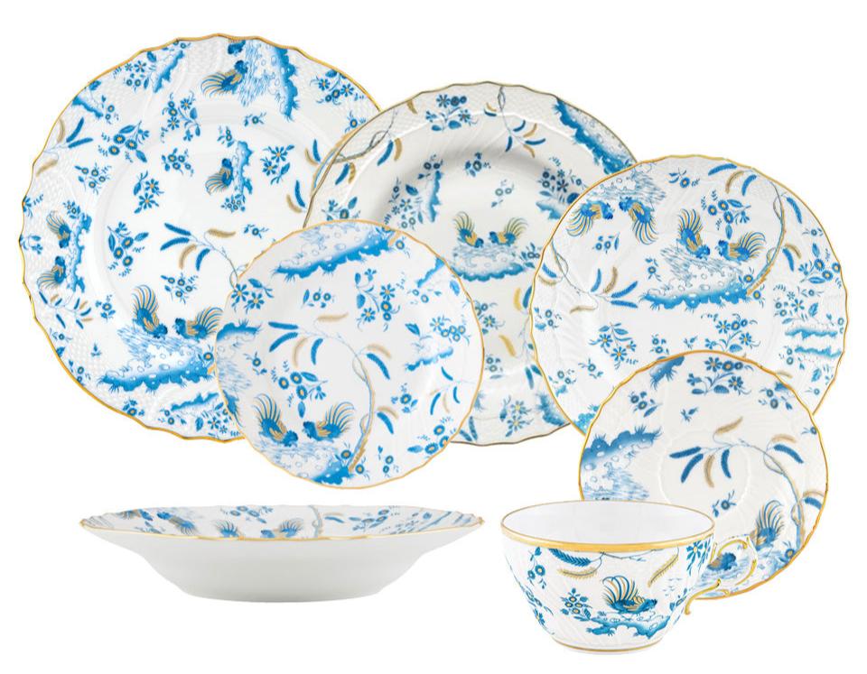 The Ginori 1735 Oro Di Doccia Turchese Dinnerware Collection is a set of seven porcelain pieces—plates, a bowl, and a cup—featuring blue floral and bird motifs with hand-painted gold trim and elegant Ji Ondori roosters.