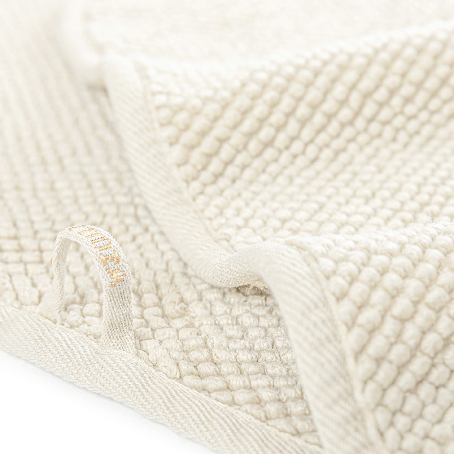Close-up of folded beige Graccioza Pearls Bath Collection fabric, featuring an ultra-soft, absorbent texture and a sewn-in loop.