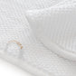 Close-up of an ultra-soft, white waffle-textured towel from the Graccioza Pearls Bath Collection by Gracciozza, featuring a decorative loop on one corner and embroidered with gold text.