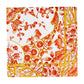 A square, eco-friendly napkin from Caspari's Gilded Porcelain Coral Collection featuring a detailed red, orange, and yellow floral and geometric pattern on a white background.
