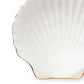 The Shell Appetizer Plate by Aerin features white ceramic in a scallop shell shape with elegant gold edging, ideal for adding coastal charm. Photographed against a white background.
