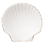 The Aerin Shell Appetizer Plate is a white ceramic plate with a scallop shell shape, ridged surface, and thin gold trim—an elegant way to bring coastal style to your table.
