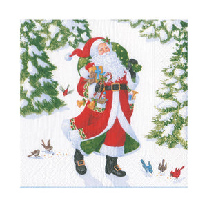 Santa from Caspari’s Woodland Santa Collection walks with a green sack through a snowy forest of birds, evergreens, and elegant paper plates—perfect festive disposable tableware for your holiday celebrations.