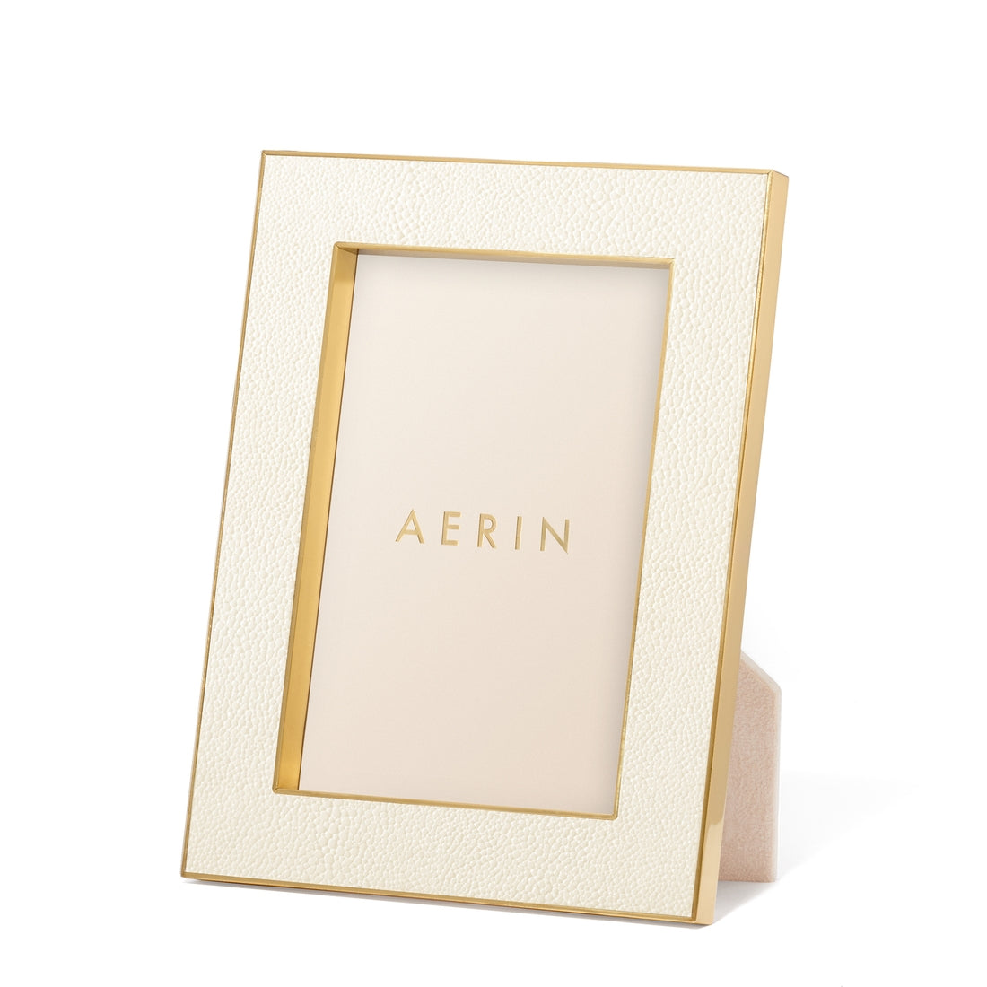 The Aerin Cream Classic Shagreen Frame Collection features a luxurious textured cream border with polished brass accents and stands upright, elegantly displaying the brand's name inside.