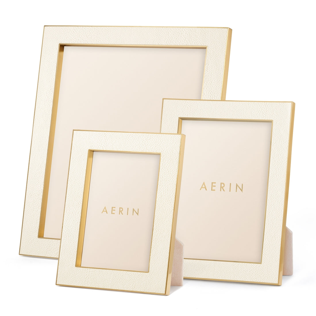 Three empty Cream Classic Shagreen frames by Aerin, in assorted sizes, are displayed upright against a white background. Polished brass accents and an elegant design highlight their luxury photo display appeal.