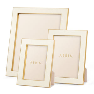 Three empty Cream Classic Shagreen frames by Aerin, in assorted sizes, are displayed upright against a white background. Polished brass accents and an elegant design highlight their luxury photo display appeal.