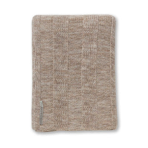 The Garmercy Throw by Alicia Adams Alpaca is a folded, beige luxury ribbed throw with a small silver tag on one edge, displayed on a white background.