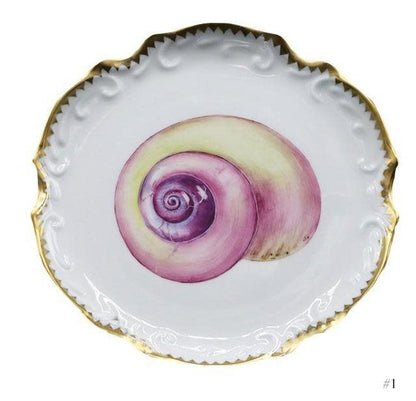 The Anna Weatherley Shell Bread and Butter Plate Collection features white porcelain plates with gold-trimmed, scalloped edges and a detailed hand-painted purple and yellow seashell design at the center.