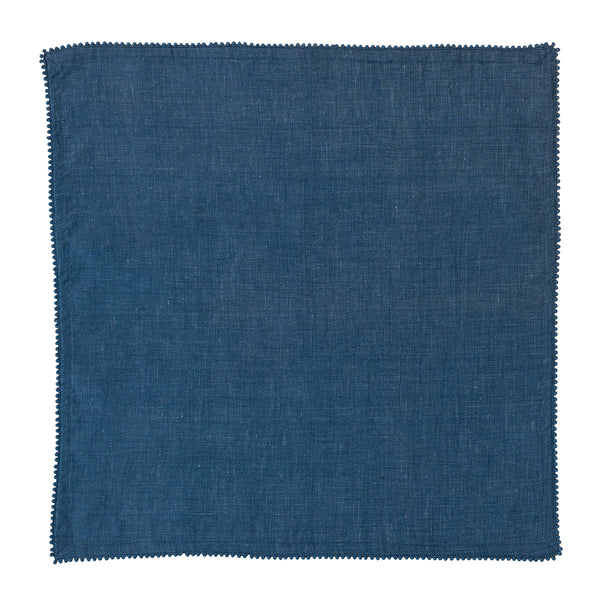 The Juliska Berry Trim Napkin Collection features a square, dark blue woven cotton napkin with a finely textured surface and delicate pom-pom trim, shown on a white background.