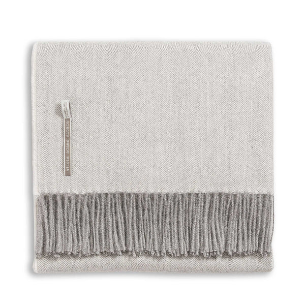 The Alicia Adams Alpaca Classic Throw in Pearl Gray Herringbone is crafted from soft alpaca fibers and features fringe along the edge.  This luxurious blanket is neatly folded and labeled, perfect as an anniversary throw.