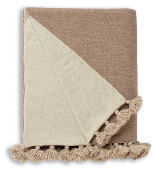 The Alicia Adams Alpaca Bali Throw in Light Taupe/Ivory is a luxurious folded blanket made from sumptuous alpaca wool, complete with fringe tassels along one edge.