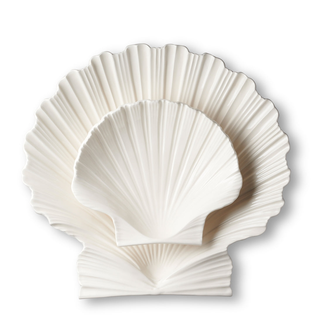 Two Cream Shell Platter Collection plates by Aerin, crafted from white earthenware in a scallop shell shape, are stacked against a plain white background, highlighting their refined coastal design.