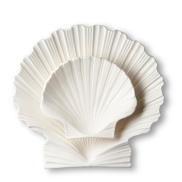 The AERIN Cream Shell Platter Collection by Aerin features three elegantly stacked white ceramic plates with a scallop shell design, creating a stylish serving platter against a plain background.