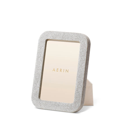 The Aerin Modern Shagreen Frame, featuring a rectangular textured design in a neutral hue, stands upright on a white background with an "AERIN" placeholder card displayed.