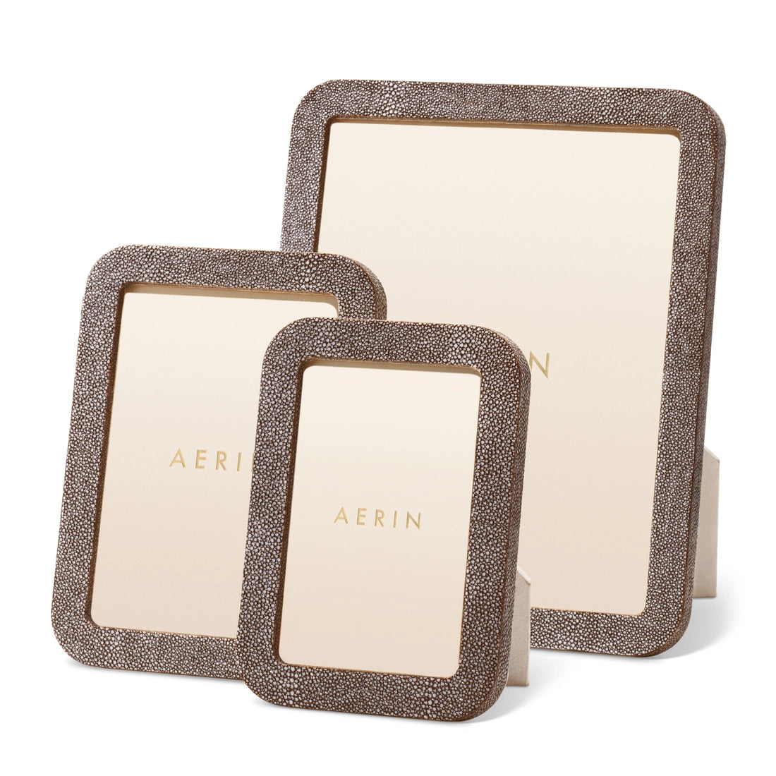 Three Modern Shagreen Frames by Aerin, in brown textured finishes and varying sizes, each feature a plain cream "AERIN" insert and are displayed against a white background.