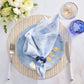 Create a fresh spring and summer table with a light blue napkin on a blue plate, Kim Seybert Herringbone Placemat in polyvinyl with gold accents, fork, knife, two glasses, and a white floral centerpiece.