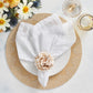 A white plate with a textured napkin and a beige flower napkin ring rests on a Kim Seybert Dream Weaver Placemat, next to two drinks and a vase of white and yellow flowers—ideal for summer entertaining.