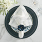 The Kim Seybert Starry Night Napkin Set, featuring white linen napkins and blue floral rings, rests on a blue and white patterned plate atop a dark charger—an elegant table accent with metallic embroidery, glassware, and cutlery on marble.