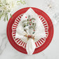 Create a festive holiday table with the Kim Seybert Christmas Carol Table Linen Collection, featuring embroidered napkins in decorative rings, paired with red and white striped plates, clear glassware, and white flowers on marble.