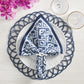 A white plate with a Kim Seybert Alfresco Napkin Set—cotton napkins featuring subtle block printing—rests on a decorative blue placemat, surrounded by glassware and pink flowers on a light tabletop.