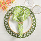 A white plate with a Kim Seybert Alfresco Napkin—cotton with a green and white block print—rests on a green woven placemat, paired with gold-rimmed glassware and orange flowers.